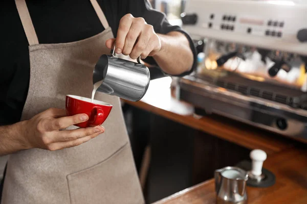 Barista pouring milk into cup of coffee in shop, closeup — Stock Photo, Image