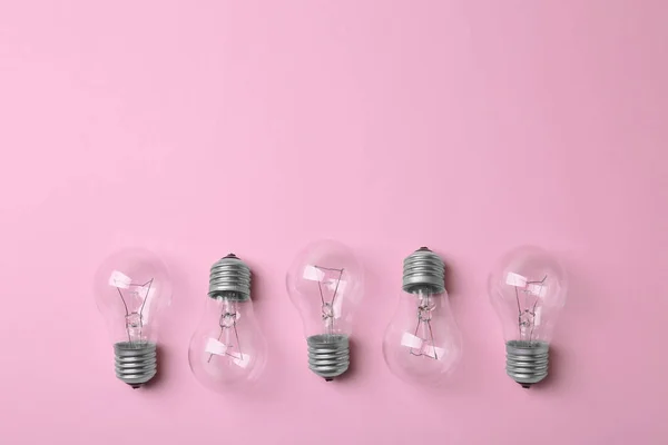Nuevas bombillas incandescentes sobre fondo rosa, vista superior. Espacio para texto — Foto de Stock