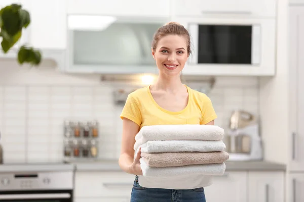 Mulher segurando toalhas limpas dobradas na cozinha. Dia de lavandaria — Fotografia de Stock