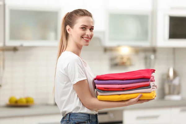 Mulher segurando dobrado roupas limpas na cozinha. Dia de lavandaria — Fotografia de Stock