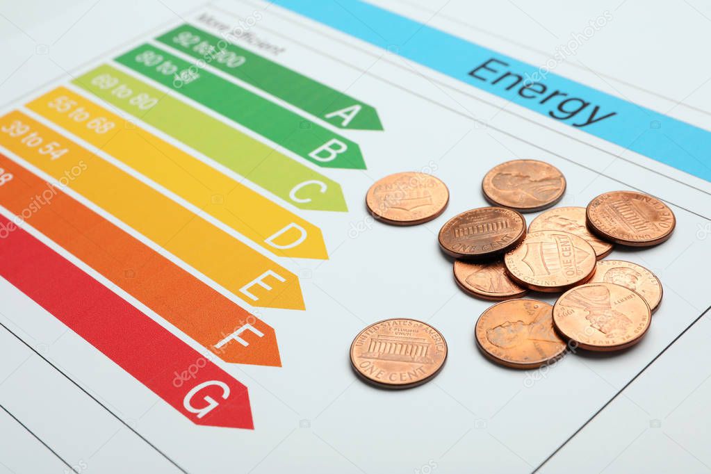 Pile of coins on energy efficiency rating chart, closeup