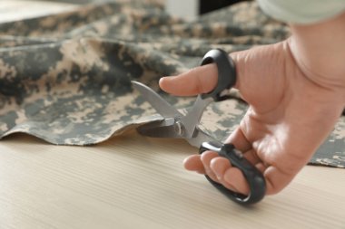 Atölye, çekim içinde makas ile profesyonel terzi kesme Kamuflaj kumaş