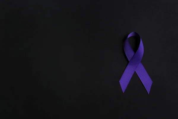 Purple awareness ribbon on black background, top view with space for text