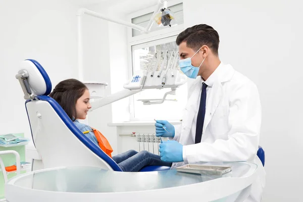Profesjonalny dentysta pracujący z małą dziewczynką w klinice — Zdjęcie stockowe