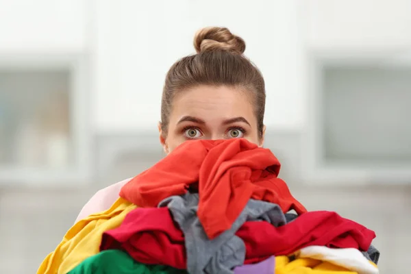 Mujer sosteniendo pila de ropa sucia en el interior — Foto de Stock