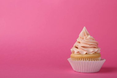 Pembe arka planda krem ile lezzetli cupcake, metin için alan