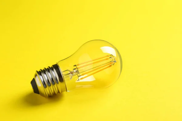 Vintage filament lamp bulb on yellow background — Stock Photo, Image