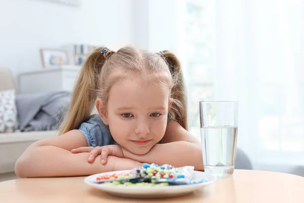 Kleines Kind mit einem Teller mit verschiedenen Pillen zu Hause. Haushaltsgefährdung — Stockfoto