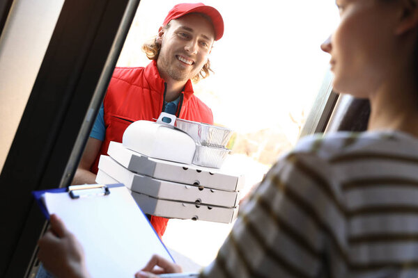 Woman receiving order from courier at door. Food delivery service