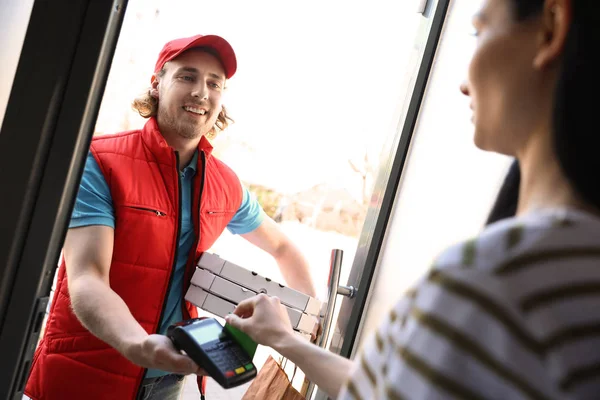 Жінка платить за доставку їжі з кредитною карткою біля дверей — стокове фото