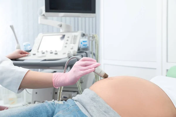 Wanita hamil muda yang sedang menjalani USG scan di klinik modern, pandangan tertutup — Stok Foto