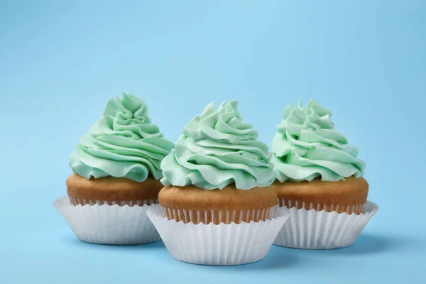Вкусные кексы со сливками на голубом фоне — стоковое фото