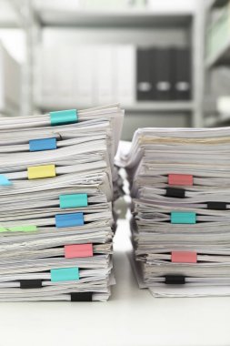 Ofis masasında kağıt kliplere sahip belgelerin yığınları