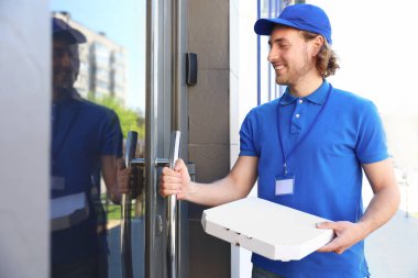 Girişinde pizza olan erkek kurye. Gıda teslimat hizmeti