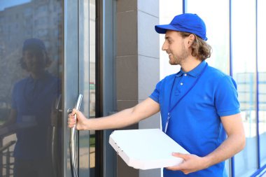 Girişinde pizza olan erkek kurye. Gıda teslimat hizmeti