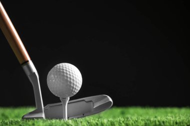 Siyah arka plan, metin alanı karşı yapay çim üzerinde kulüp ile golf topu vurmak