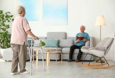 Evde yürüyüş çerçevesi ve kocası kullanarak yaşlı kadın