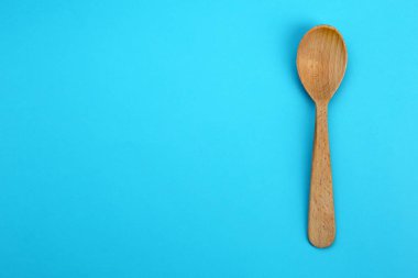 Mavi arka planda temiz boş ahşap kaşık, üst görünüm. Metin alanı