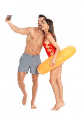 Genç çekici çift içinde Beachwear ile şişme yüzük alma selfie üzerinde beyaz arka plan
