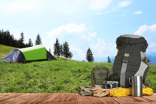 Set met verschillende kampeerspullen op houten tafel in Bergen — Stockfoto