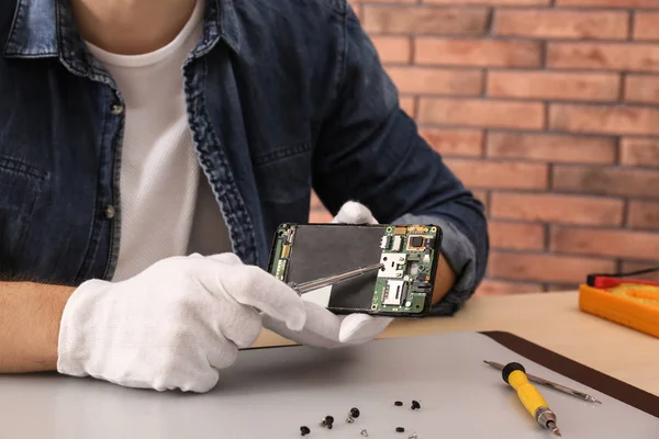 Técnico de reparación de teléfonos inteligentes rotos en la mesa, primer plano. Espacio para texto —  Fotos de Stock