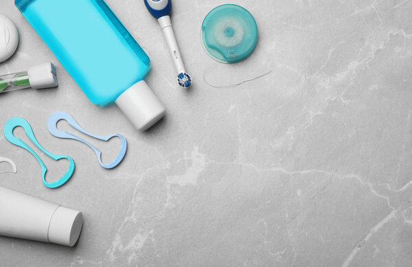 Flat lay composition with tongue cleaners and teeth care products on grey background. Space for text