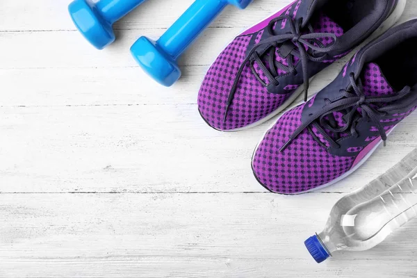 Flat lay composition with dumbbells, sneakers and space for text on wooden background — Stock Photo, Image