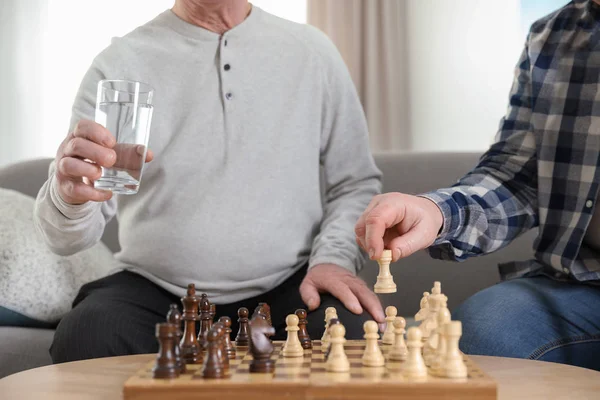 Пожилые мужчины играют в шахматы в доме престарелых, крупным планом. Помощь пожилым людям — стоковое фото