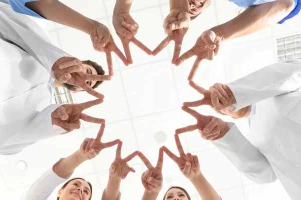 Equipo de trabajadores médicos tomados de la mano en el hospital, vista inferior. Concepto de unidad — Foto de Stock