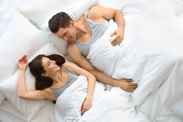 Adorável jovem casal descansando na cama grande, vista acima — Fotografia de Stock