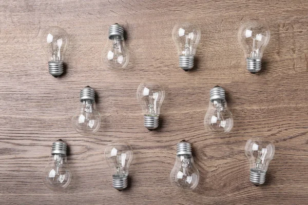 New incandescent lamp bulbs on wooden background, top view