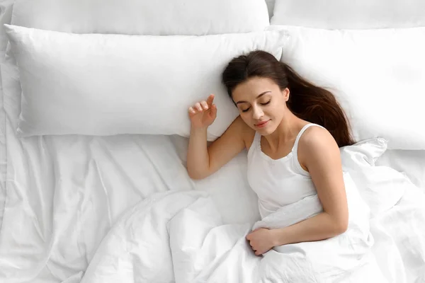 Retrato de bela jovem mulher dormindo em cama grande, vista acima — Fotografia de Stock