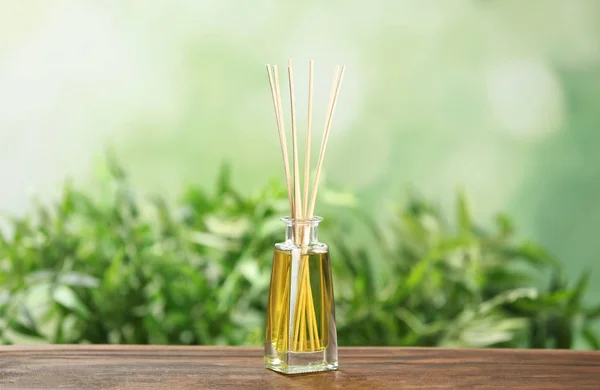 Reed ambientador de ar na mesa de madeira contra fundo verde desfocado — Fotografia de Stock