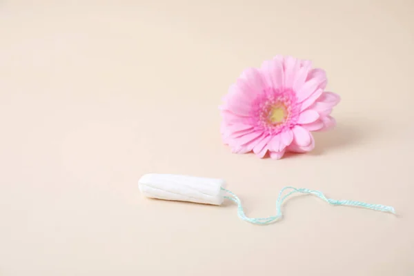 Hygienic tampon and flower on beige background. Gynecology concept — Stock Photo, Image