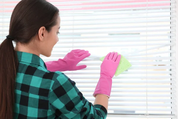 Vrouw schoonmaken raam jaloezieën met Rag binnenshuis — Stockfoto