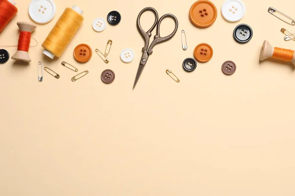 Flat lay composition with scissors and other sewing accessories on light yellow background, space for text