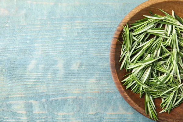 Ciotola di legno con rosmarino fresco sul tavolo a colori, posa piatta. Spazio per testo — Foto Stock