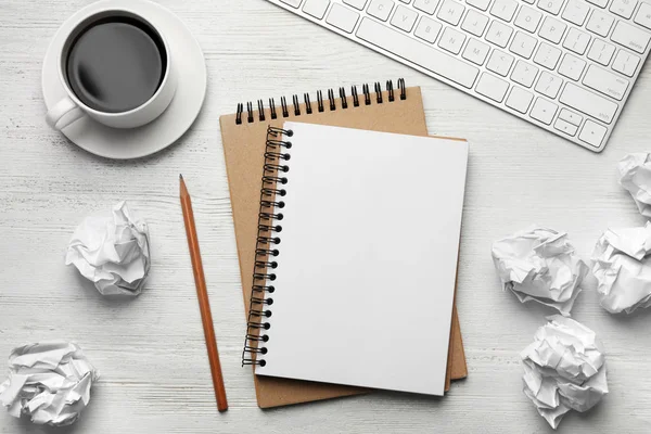 Platte lay compositie met lege notebook en verfrommeld papieren ballen op witte houten tafel. Ruimte voor tekst — Stockfoto