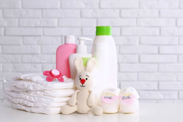 Acessórios de bebê na mesa perto da parede de tijolo branco. Espaço para texto — Fotografia de Stock