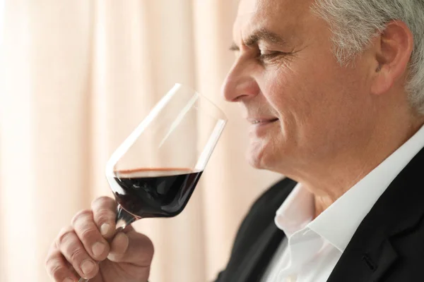 Senior man med glas vin inomhus — Stockfoto