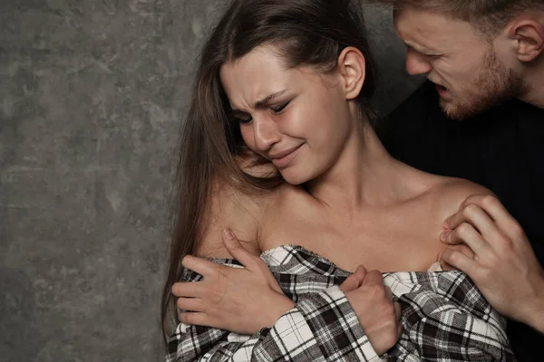 Man abusing young woman on grey background, space for text. Stop sexual assault — Stock Photo, Image