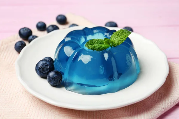 Piatto di deliziosa gelatina blu con bacche su sfondo di legno rosa — Foto Stock