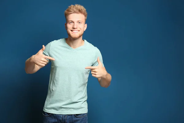 Un joven con una camiseta en blanco sobre fondo azul. Burla para el diseño —  Fotos de Stock