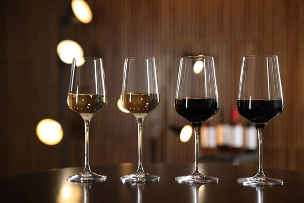 Copos de diferentes vinhos na mesa contra fundo desfocado — Fotografia de Stock