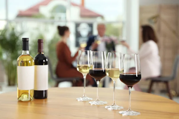 Bouteilles et verres avec différents vins sur la table sur fond flou — Photo