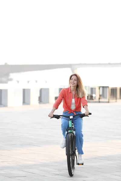 Młoda kobieta jeździ rowerem w mieście w słoneczny dzień — Zdjęcie stockowe