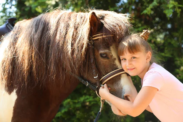 Милая маленькая девочка со своим пони в зеленом парке — стоковое фото