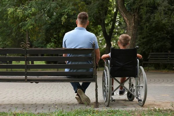 Pai com seu filho em cadeira de rodas no parque — Fotografia de Stock