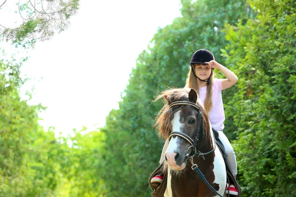 Linda niña montando pony en el parque verde — Foto de Stock
