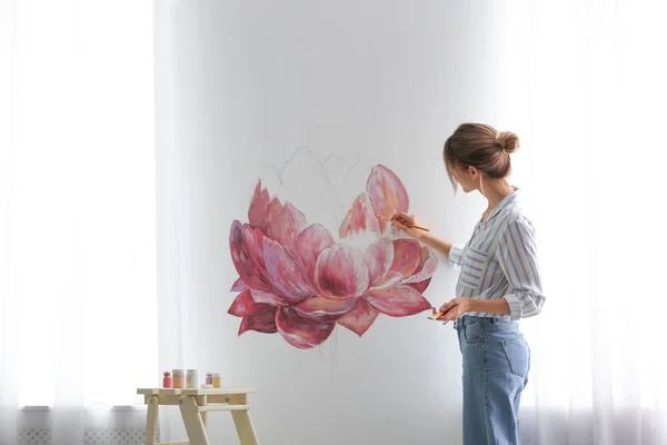 Decorador de flores de pintura en la pared blanca en la habitación. Diseño de interiores — Foto de Stock